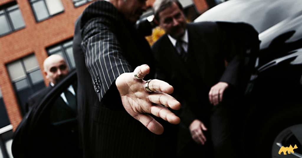 A chauffeur helping a guest out of a vehicle whilst shielding them from unwanted photography