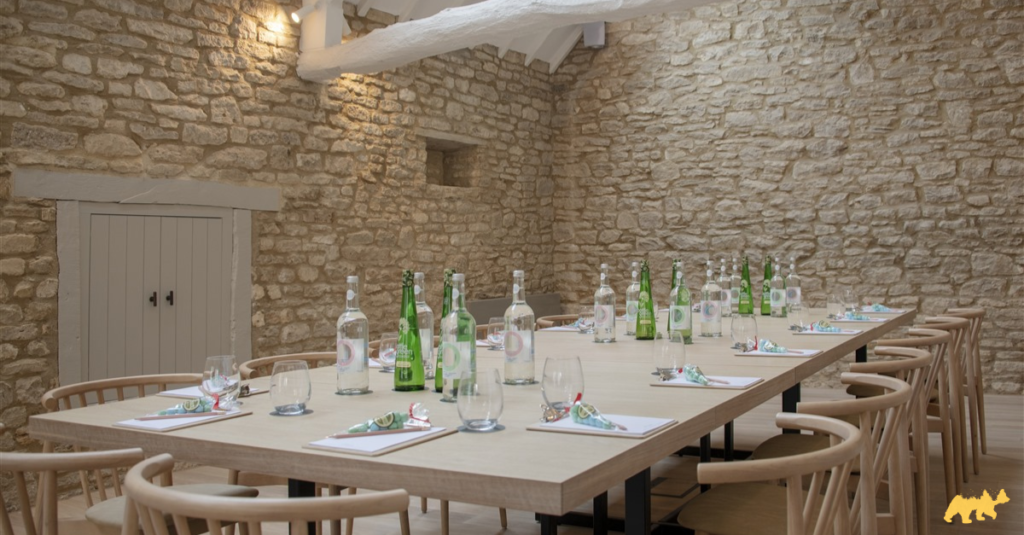 A beautiful meeting room table, set with a Cotswold stone room, adorned with white linen and tulle swathes.